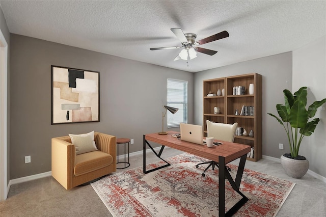 carpeted home office featuring a textured ceiling and ceiling fan