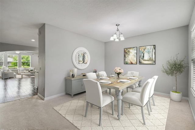 dining room featuring ceiling fan with notable chandelier and light carpet