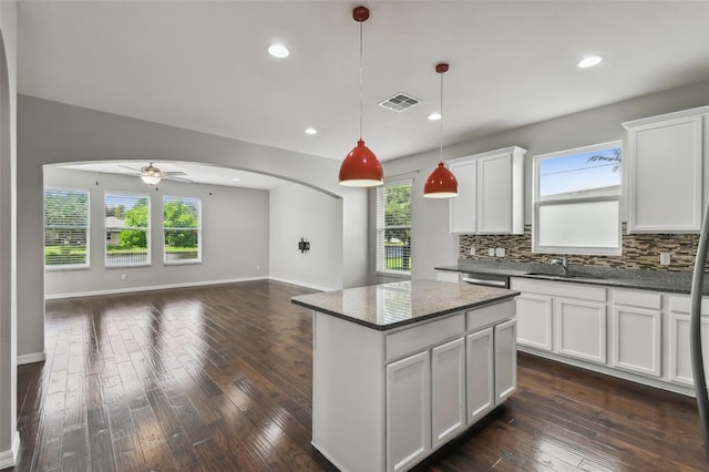 kitchen with dark wood-type flooring, decorative backsplash, hanging light fixtures, sink, and white cabinetry