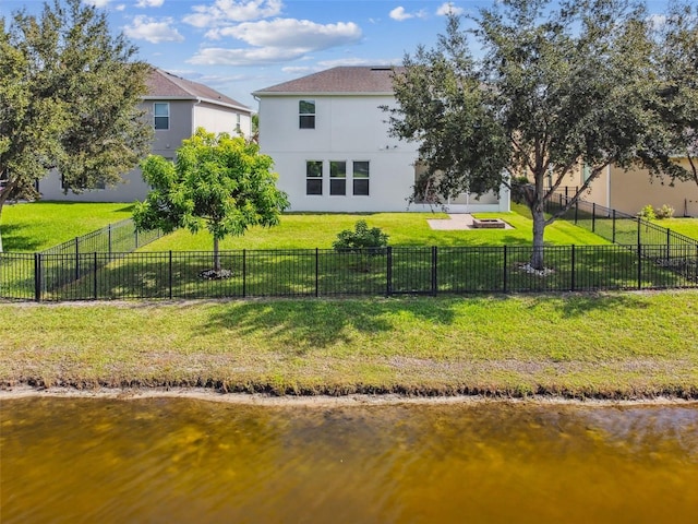 rear view of house with a lawn and a water view