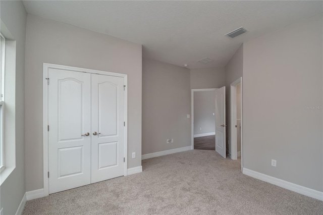 unfurnished bedroom featuring light carpet and a closet