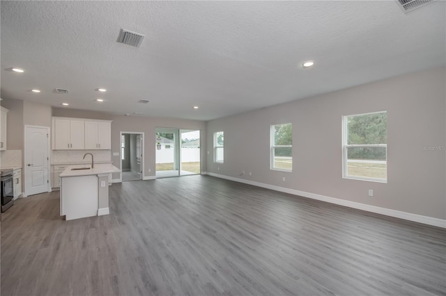 kitchen with an island with sink, white cabinetry, stainless steel range oven, light hardwood / wood-style floors, and sink