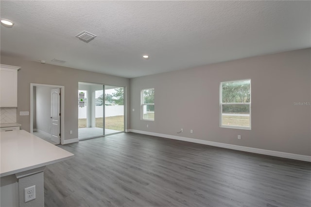 unfurnished living room with a textured ceiling and dark hardwood / wood-style flooring