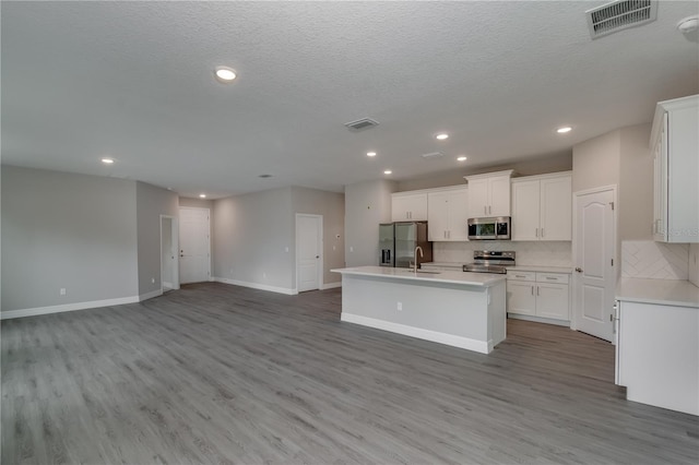 kitchen with white cabinetry, a kitchen island with sink, hardwood / wood-style flooring, sink, and stainless steel appliances