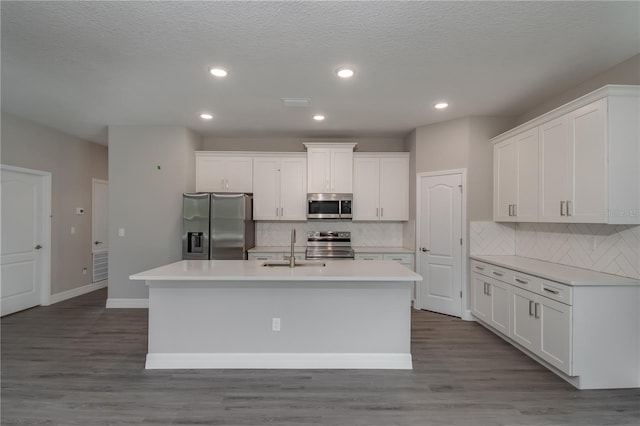 kitchen featuring white cabinetry, appliances with stainless steel finishes, hardwood / wood-style floors, and a kitchen island with sink