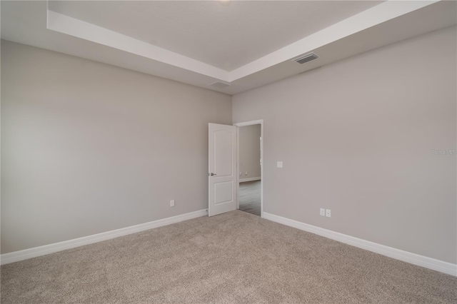 carpeted empty room with a raised ceiling