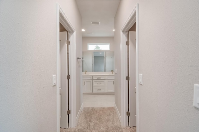 hall with light carpet and sink