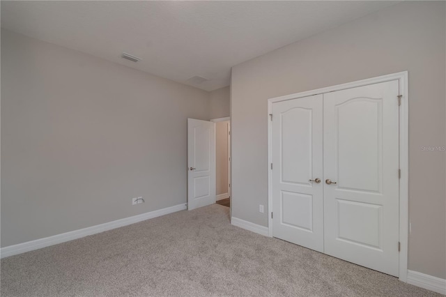 unfurnished bedroom featuring light colored carpet and a closet