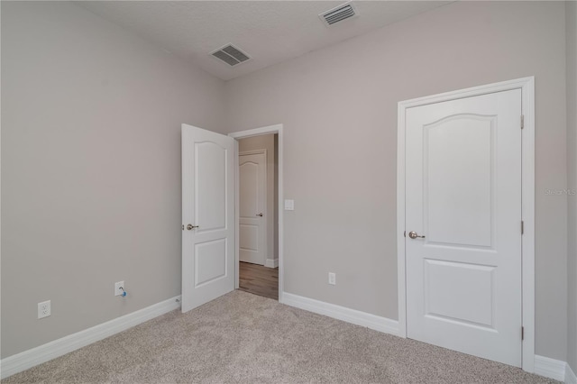 unfurnished bedroom featuring a textured ceiling and light colored carpet