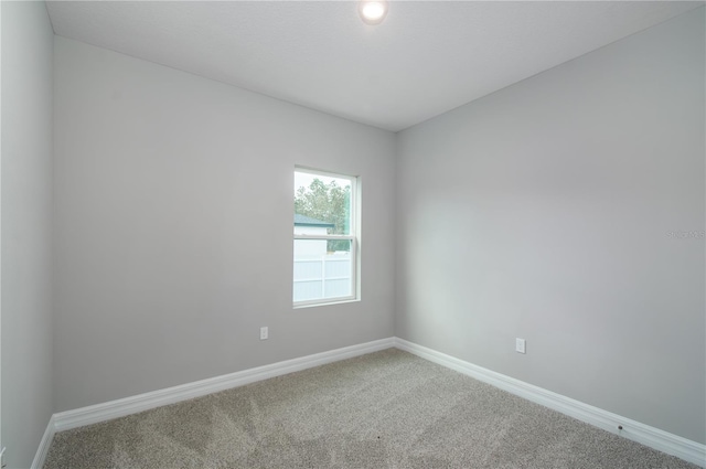 carpeted empty room featuring baseboards