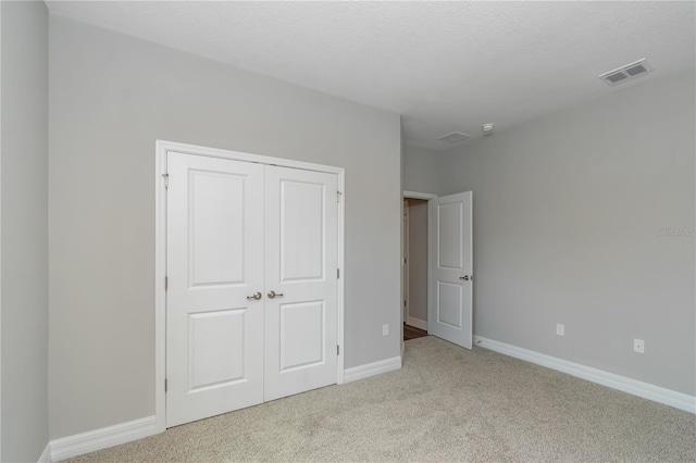 unfurnished bedroom featuring light carpet, baseboards, visible vents, and a closet