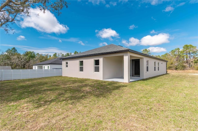 rear view of property featuring a patio area, fence, stucco siding, and a yard