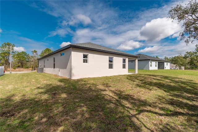 back of property with central AC unit, a lawn, and stucco siding