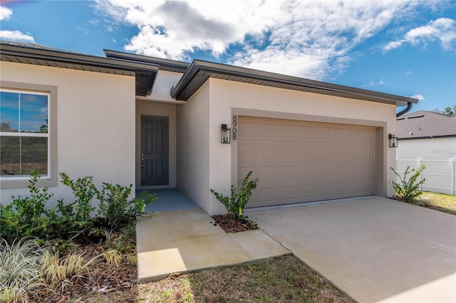 view of front facade with a garage, driveway, and stucco siding