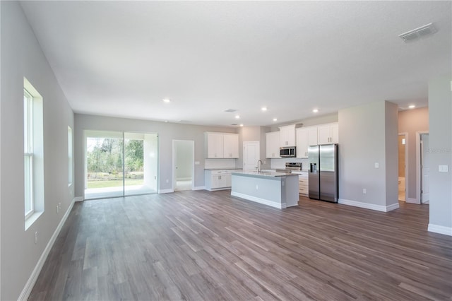 kitchen featuring stainless steel appliances, dark wood-style flooring, visible vents, open floor plan, and an island with sink