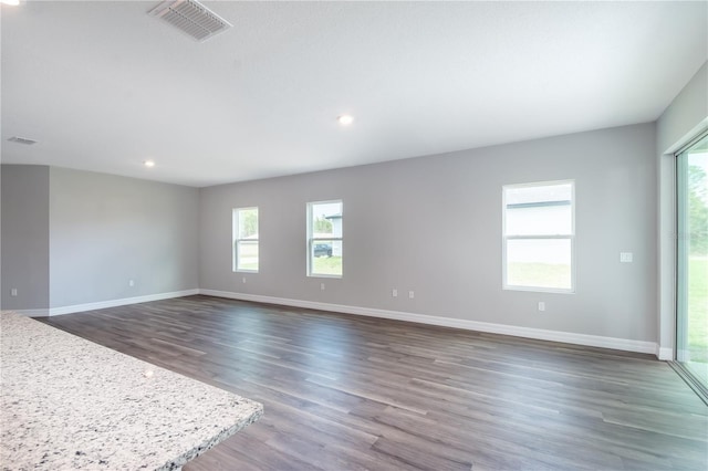 spare room featuring dark wood-style flooring, visible vents, and baseboards