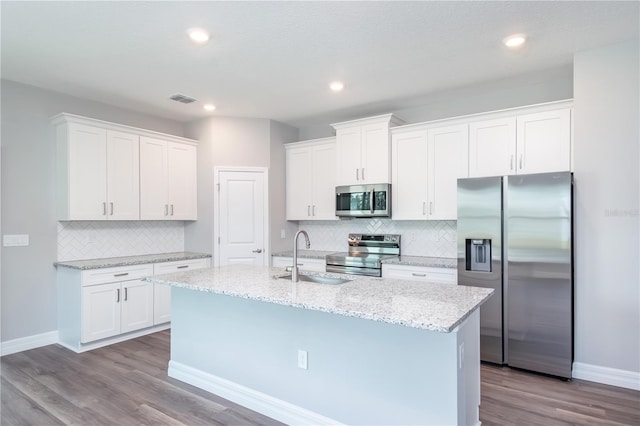 kitchen with stainless steel appliances, a sink, visible vents, white cabinets, and a center island with sink