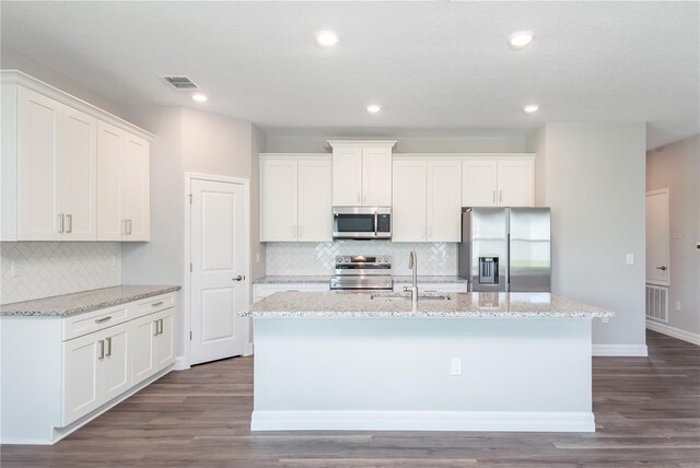 kitchen with appliances with stainless steel finishes, visible vents, a sink, and an island with sink