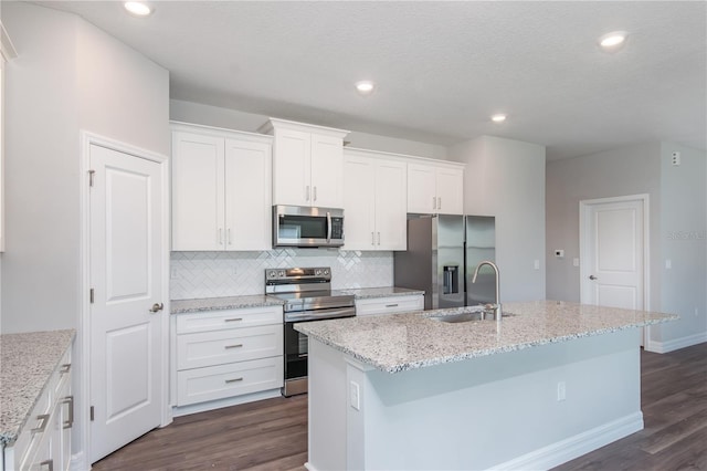 kitchen featuring dark wood finished floors, appliances with stainless steel finishes, a kitchen island with sink, white cabinetry, and a sink