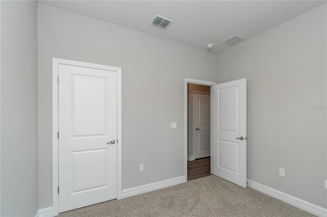 unfurnished bedroom with carpet, visible vents, and baseboards