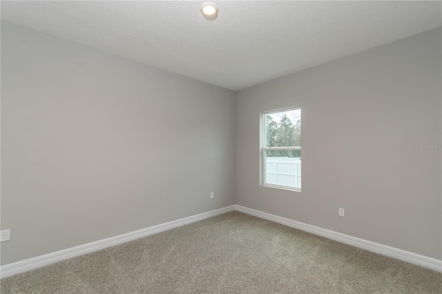 unfurnished room with light carpet, baseboards, and a textured ceiling