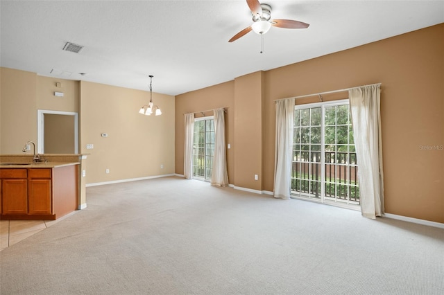 unfurnished living room with light carpet, sink, and ceiling fan with notable chandelier