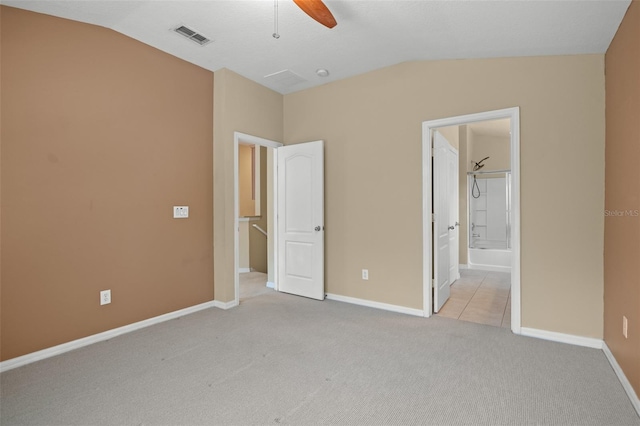 unfurnished bedroom with connected bathroom, vaulted ceiling, light carpet, and ceiling fan