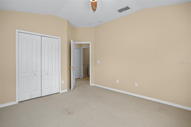 unfurnished bedroom featuring light carpet, a closet, vaulted ceiling, and ceiling fan