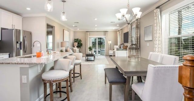 dining area featuring ornamental molding, sink, light tile patterned flooring, and an inviting chandelier