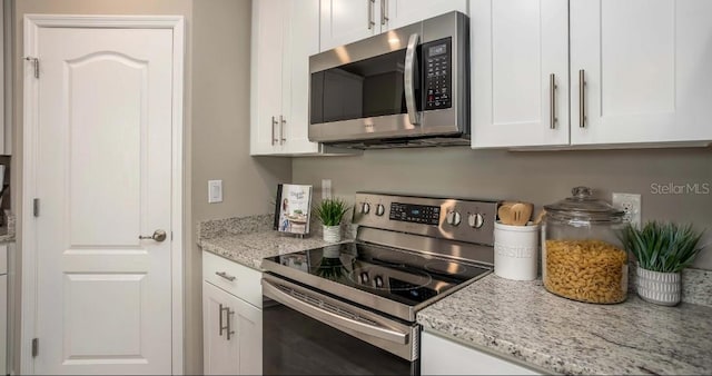 kitchen with appliances with stainless steel finishes, light stone counters, and white cabinets