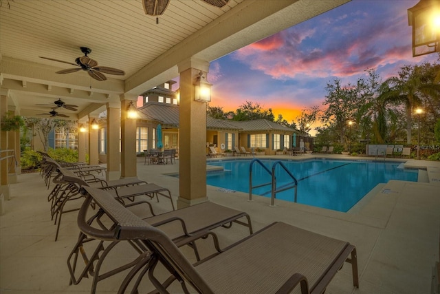 pool at dusk featuring ceiling fan and a patio