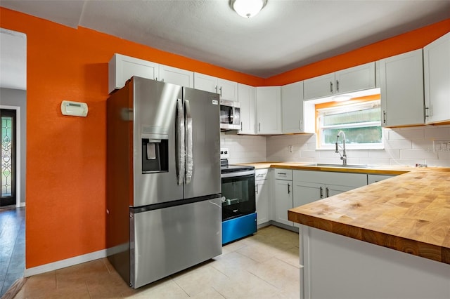 kitchen with white cabinets, wooden counters, sink, and appliances with stainless steel finishes