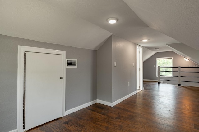 bonus room featuring dark hardwood / wood-style flooring, lofted ceiling, and a textured ceiling