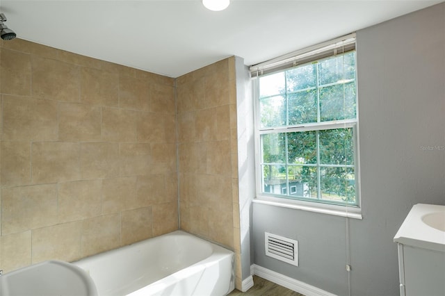 bathroom with vanity, tiled shower / bath, and wood-type flooring