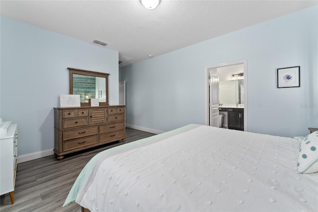 bedroom with ensuite bathroom, a textured ceiling, and hardwood / wood-style floors