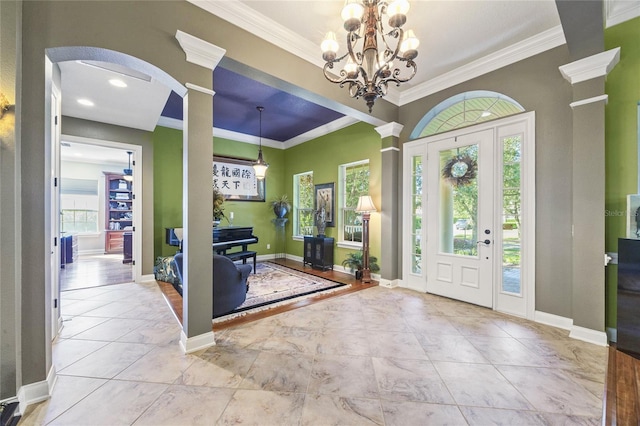 foyer featuring a notable chandelier, ornamental molding, and decorative columns