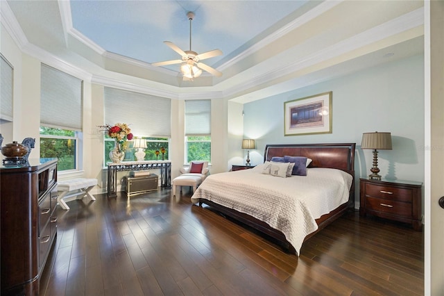 bedroom with ceiling fan, dark hardwood / wood-style flooring, crown molding, and a tray ceiling