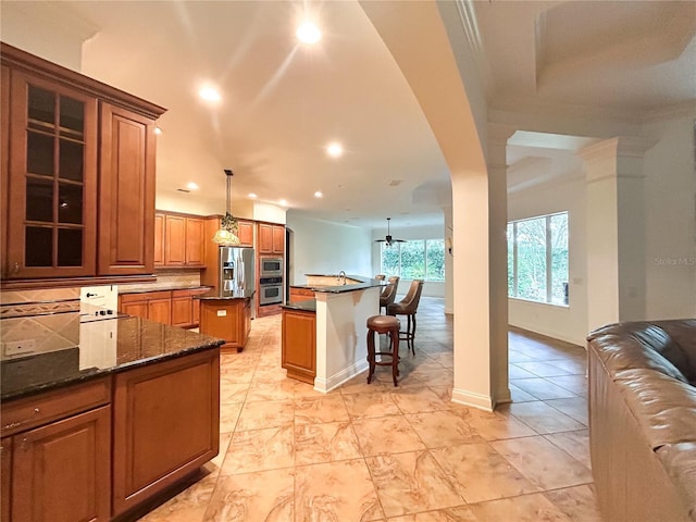 kitchen featuring tasteful backsplash, stainless steel appliances, ceiling fan, decorative light fixtures, and a kitchen island