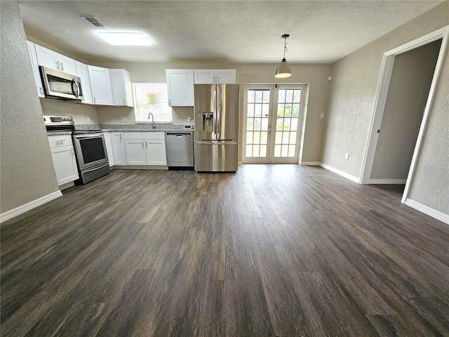 kitchen with stainless steel appliances, white cabinetry, sink, hanging light fixtures, and dark wood-type flooring