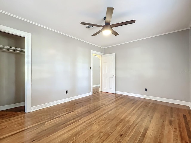 unfurnished bedroom with ornamental molding, a closet, hardwood / wood-style floors, and ceiling fan