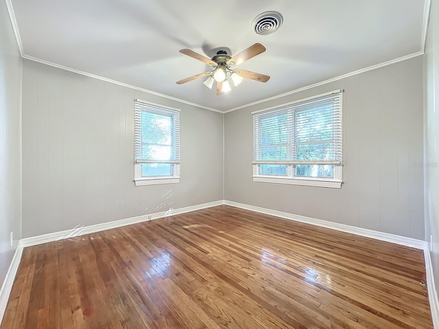 spare room featuring ornamental molding, wooden walls, wood-type flooring, and ceiling fan