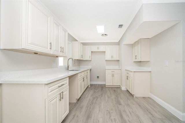 kitchen with white cabinets, sink, and light wood-type flooring