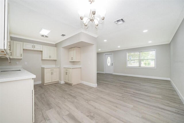 kitchen featuring a chandelier, ornamental molding, light hardwood / wood-style floors, decorative light fixtures, and sink