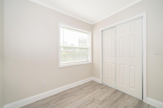 unfurnished bedroom featuring a closet, ornamental molding, and light wood-type flooring