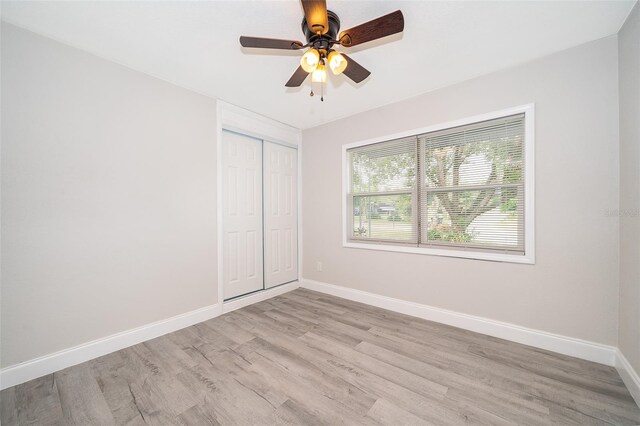 unfurnished bedroom with light hardwood / wood-style flooring, a closet, and ceiling fan