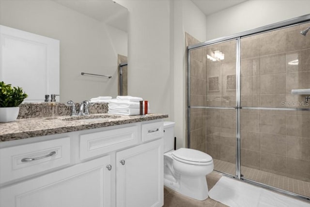 bathroom featuring vanity, toilet, tile patterned floors, and a shower with door