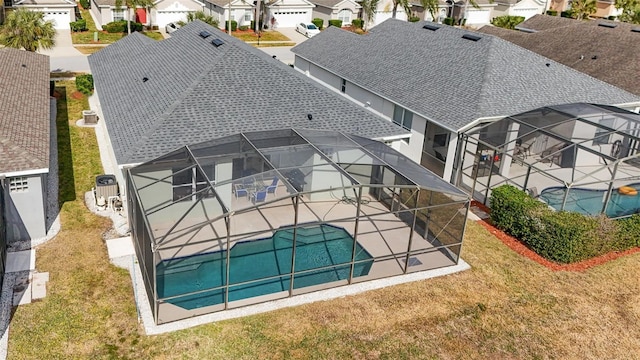 exterior space featuring a lawn, glass enclosure, and a patio area