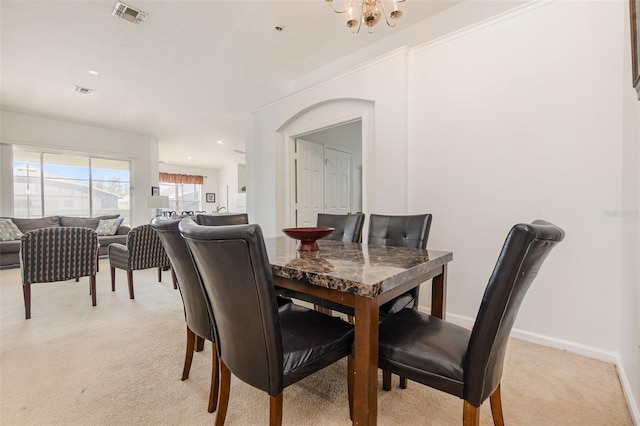 dining area with light colored carpet and a notable chandelier