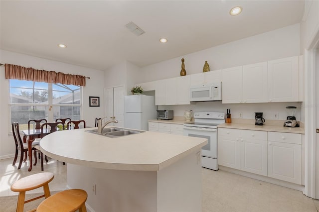 kitchen featuring white cabinets, sink, a kitchen island with sink, and white appliances