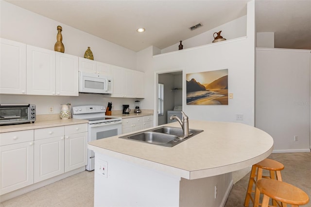 kitchen featuring a breakfast bar, sink, an island with sink, white appliances, and white cabinets